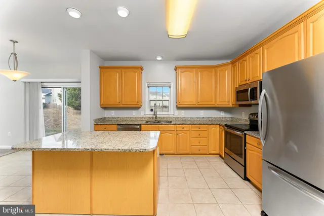 a large kitchen with granite countertop a sink stainless steel appliances and cabinets