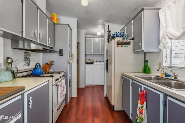 a kitchen with stainless steel appliances granite countertop a refrigerator a stove a sink and wooden floor