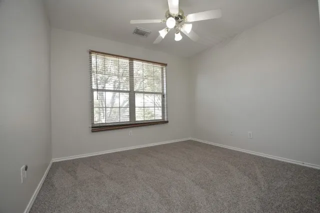 an empty room with a window and a fan