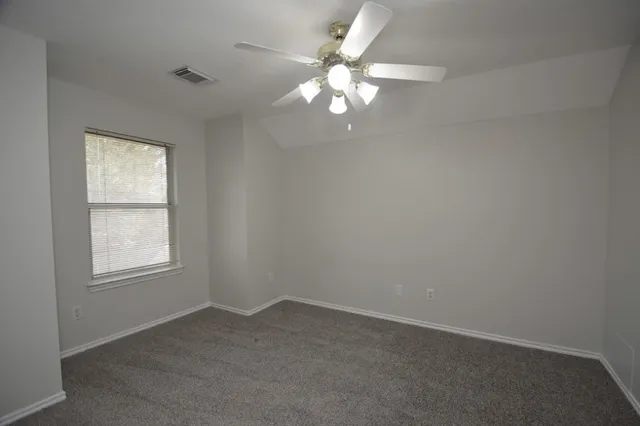 an empty room with a chandelier fan and windows