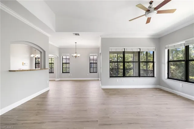 a view of an empty room with a window and wooden floor