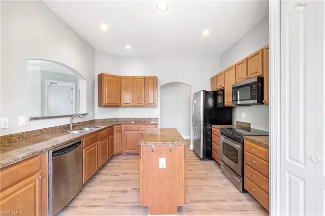 a large kitchen with stainless steel appliances granite countertop a stove refrigerator and a sink