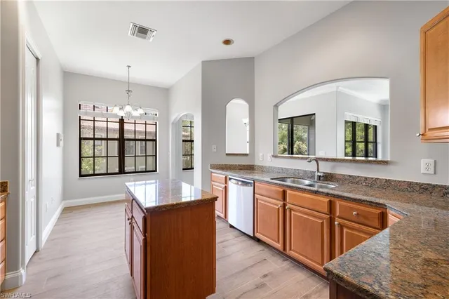 a large kitchen with kitchen island granite countertop wooden floor a sink and stainless steel appliances