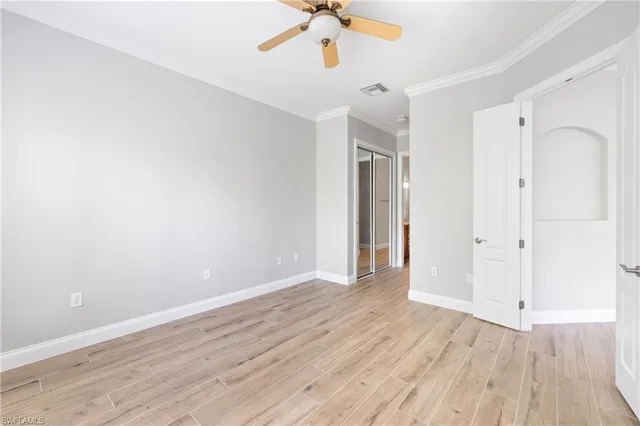 an empty room with wooden floor fan and windows