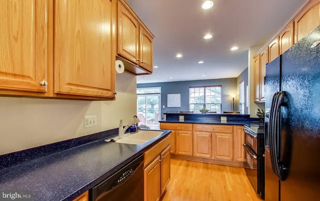 a kitchen with stainless steel appliances granite countertop a refrigerator a sink a stove and a wooden cabinets