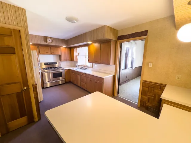 a large kitchen with a stove a refrigerator a sink a dining table and chairs with wooden floor