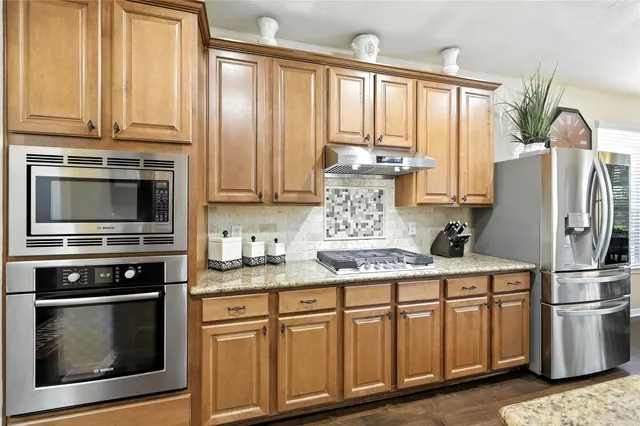a kitchen with granite countertop a table chairs stove a sink and dishwasher