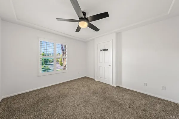 an empty room with a ceiling fan and windows
