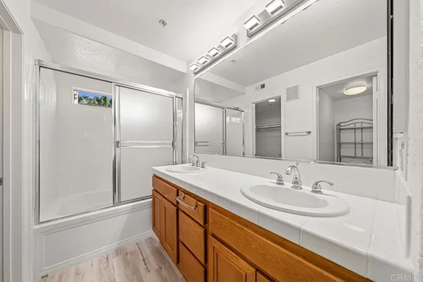 a bathroom with a sink double vanity granite tub shower and a mirror
