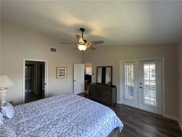 a bedroom with a bed and dresser with wooden floor