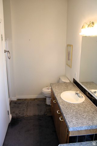 22580 Spring Creek Drive, Unit B61 Fairview, UT 84629 - Photo 24 of 39 Bathroom featuring a wood-finish vanity with a granite-look countertop, an integrated sink, and a framed wall mirror