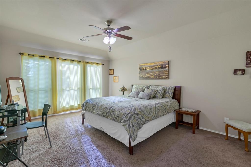 520 Rustic Oak Lane McKinney, TX 75072 - Photo 21 of 37 a spacious bedroom with a bed a chandelier and large mirror