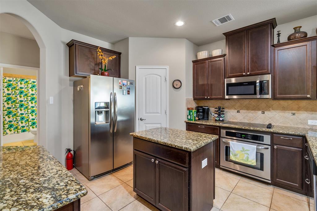 520 Rustic Oak Lane McKinney, TX 75072 - Photo 9 of 37 a kitchen with stainless steel appliances granite countertop a stove a refrigerator and a sink
