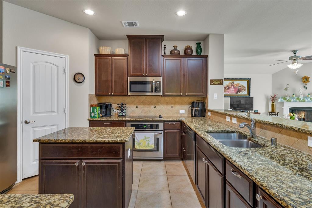 520 Rustic Oak Lane McKinney, TX 75072 - Photo 10 of 37 a kitchen with stainless steel appliances granite countertop a sink stove microwave and refrigerator