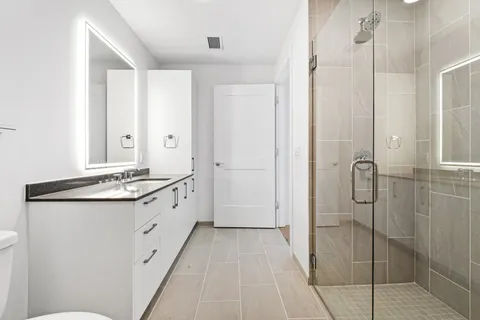a spacious bathroom with a granite countertop sink a mirror and shower