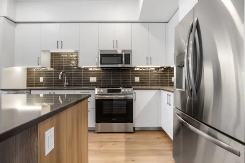 a kitchen with stainless steel appliances granite countertop a refrigerator a stove and a sink