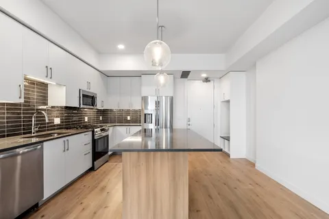 a large kitchen with stainless steel appliances granite countertop a lot of counter space and wooden floors