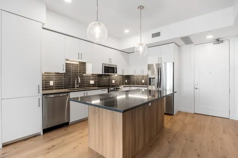 a kitchen with stainless steel appliances granite countertop a sink a refrigerator and a stove