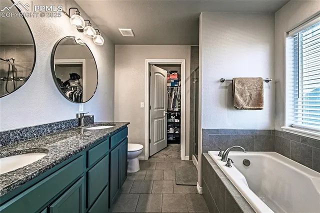 a bathroom with a granite countertop sink and a bathtub