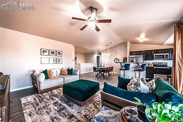 a living room with furniture kitchen view and a chandelier