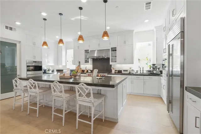 a kitchen with stainless steel appliances granite countertop a sink a stove a refrigerator and island with wooden floor