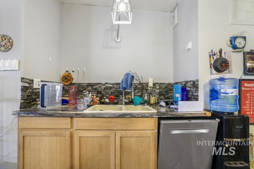 315 Wilson Street Eden, ID 83325 - Photo 7 of 30 Indoor wet bar featuring light wood finish cabinets, stainless steel dishwasher, and tasteful backsplash