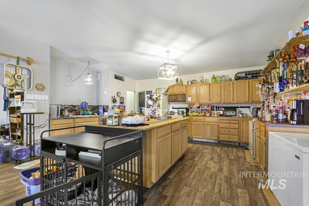 315 Wilson Street Eden, ID 83325 - Photo 9 of 30 Kitchen with dark wood-style floors, a kitchen island, decorative light fixtures, and light wood finish cabinetry