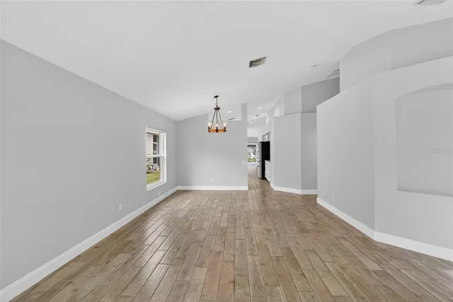 a view of empty room with wooden floor and window