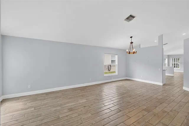 a view of an empty room with a window and wooden floor