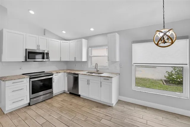 a kitchen with stainless steel appliances granite countertop a refrigerator a sink dishwasher a stove and a refrigerator with wooden floor