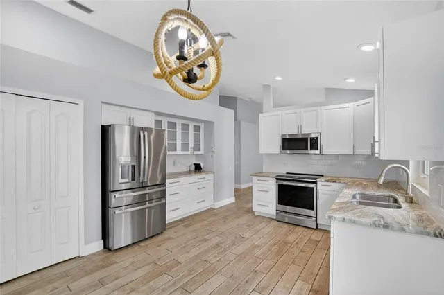 a kitchen with counter top space stainless steel appliances and wooden floor