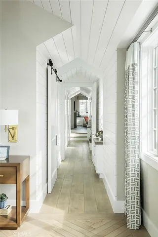 a view of a hallway with wooden floor and a living room