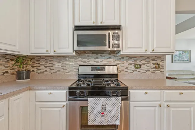 a kitchen with granite countertop white cabinets and stainless steel appliances
