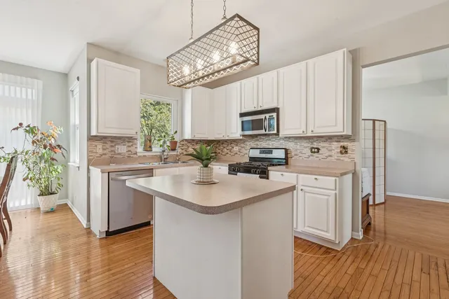 a kitchen with kitchen island granite countertop a sink cabinets a counter top space and stainless steel appliances