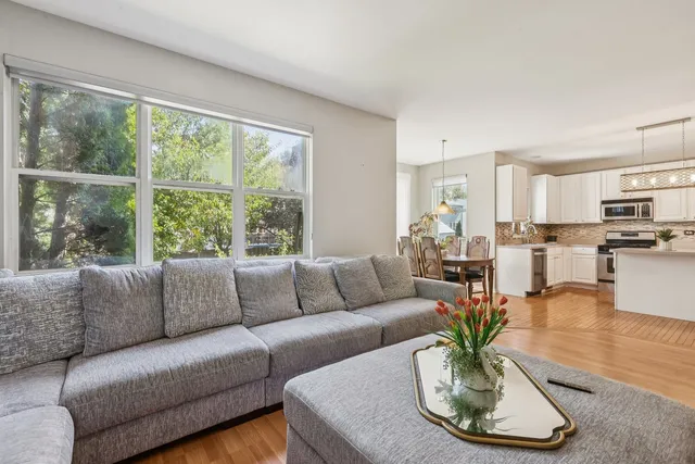 a living room with furniture kitchen view and a large window