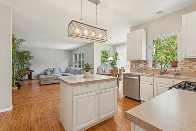 a kitchen with a sink dishwasher a stove and white cabinets with wooden floor