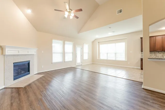 an empty room with wooden floor fireplace and window