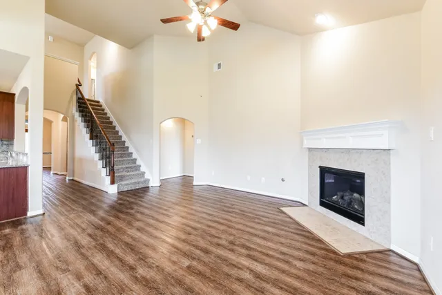 a view of an empty room with wooden floor fan and a fireplace