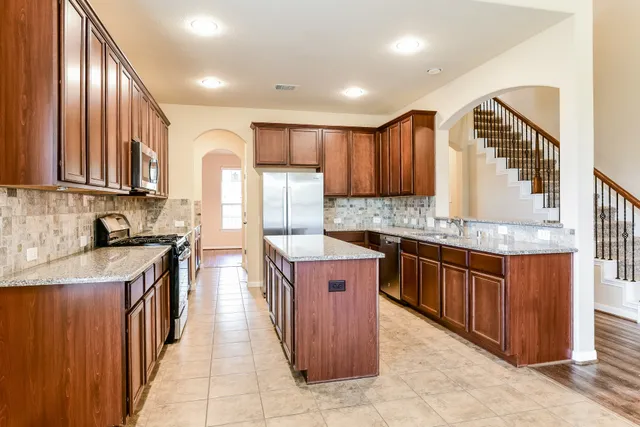 a kitchen with stainless steel appliances granite countertop wooden cabinets a sink and a oven