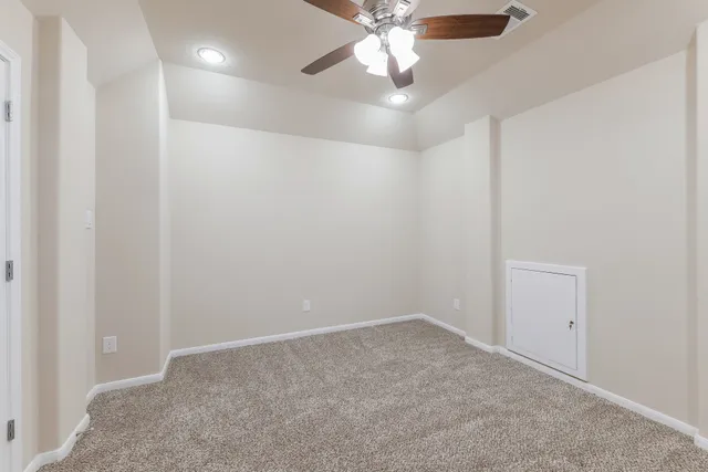 an empty room with a chandelier fan and windows