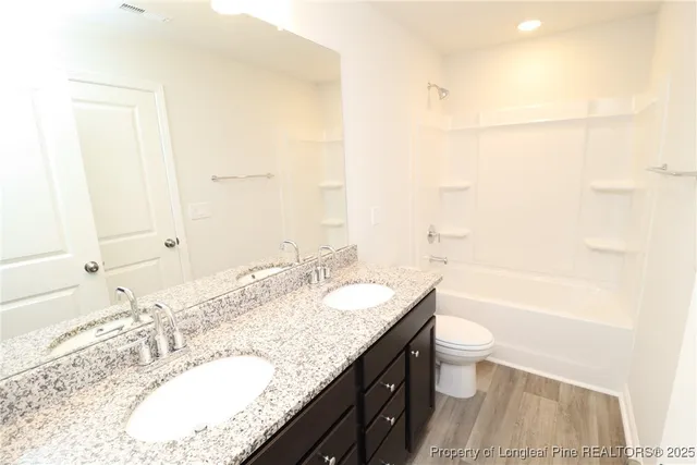 a bathroom with a granite countertop sink a toilet and bathtub