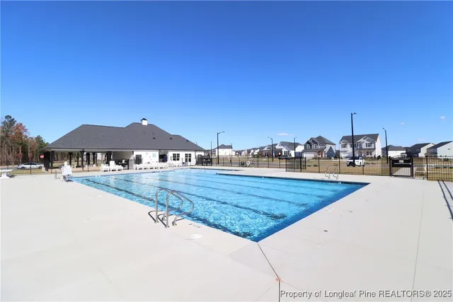 a view of swimming pool with outdoor seating and house in the background