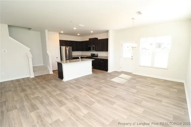 a view of a kitchen with kitchen island a sink wooden floor and counter top space