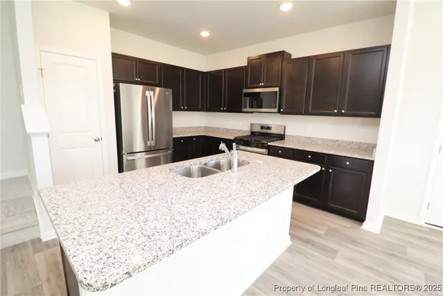 a kitchen with stainless steel appliances kitchen island granite countertop a refrigerator and a sink