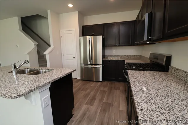 a kitchen with granite countertop wooden cabinets a refrigerator and a sink