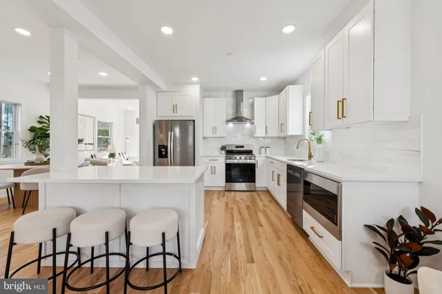 a kitchen with stainless steel appliances kitchen island granite countertop a stove top oven a sink a dining table and chairs with wooden floor