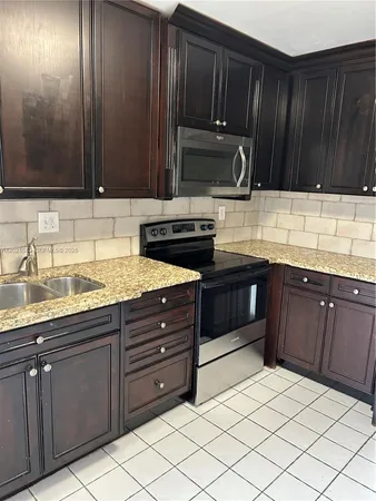 a kitchen with granite countertop wooden cabinets and stainless steel appliances