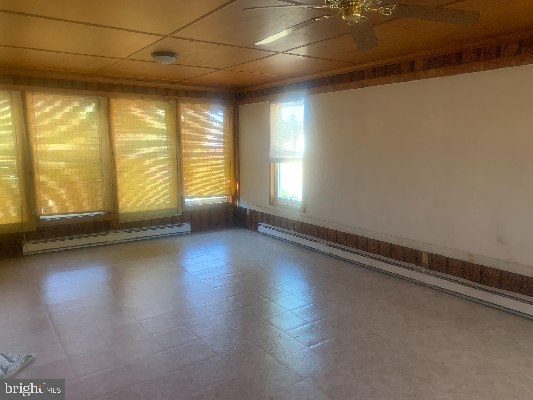 915 Stone Road, Unit A Laurel Springs, NJ 08021 - Photo 5 of 13 an empty room with wooden floor and windows with curtains