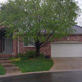 a front view of a house with a garden and trees