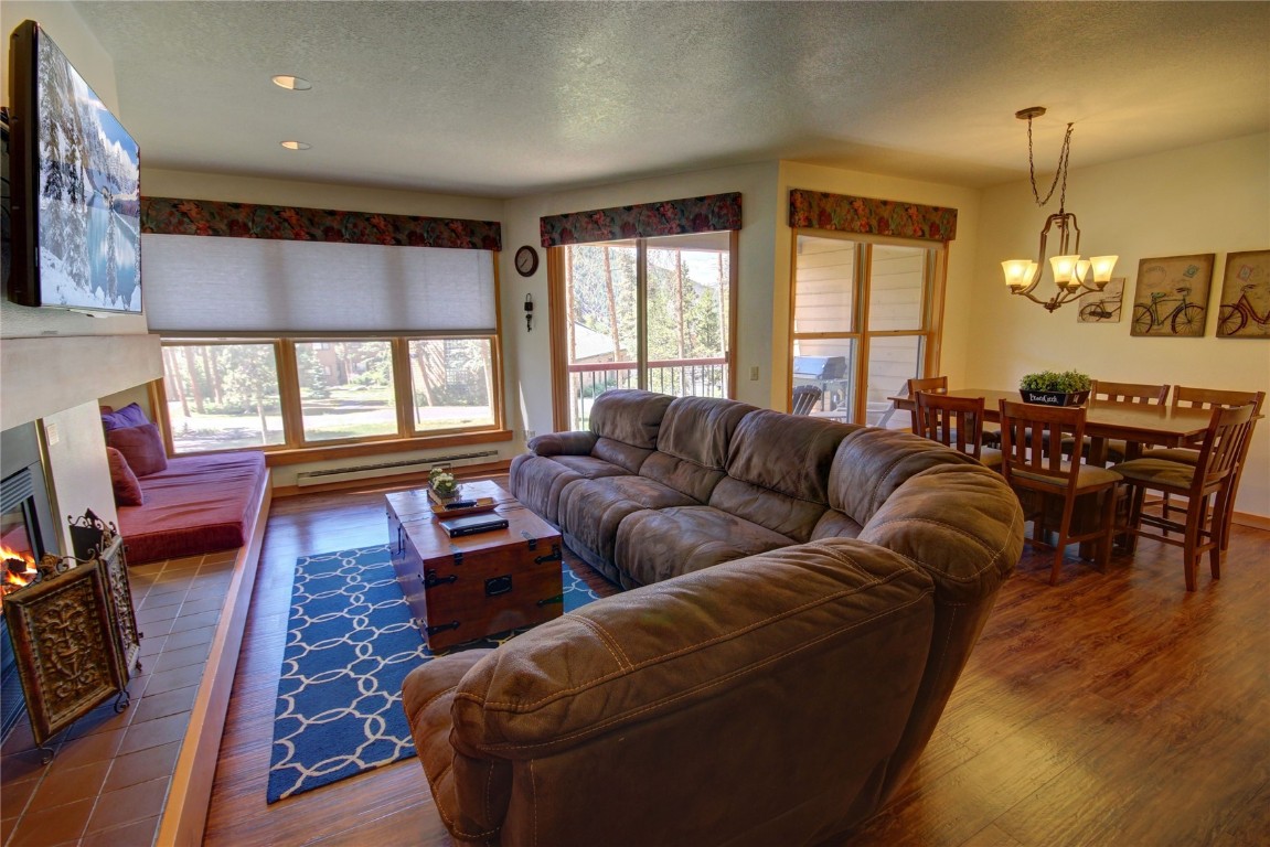 180 Tennis Club Road, Unit 1648 Keystone, CO 80435 - Photo 10 of 18 Living room featuring dark hardwood / wood-style floors, a textured ceiling, baseboard heating, a fireplace, and a notable chandelier